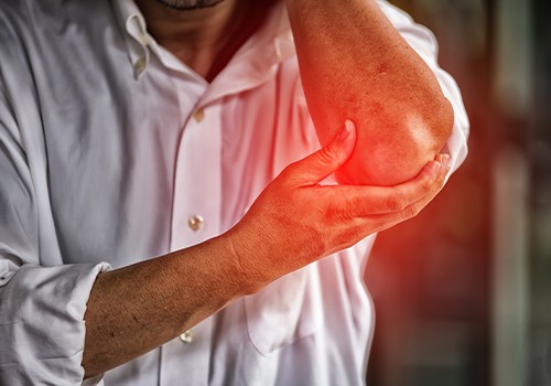 Man holding elbow in pain before laser therapy