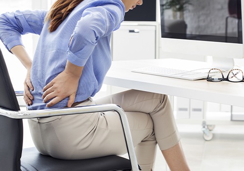 Woman with herniated disc holding her lower back