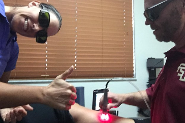 Chiropractor treating smiling patient who is giving a thumbs up