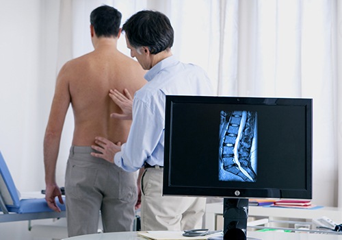 Chiropractor assessing patient with low back pain