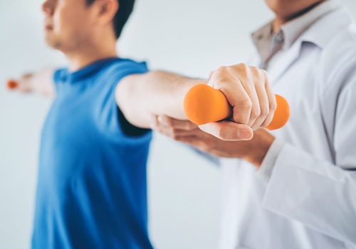 Chiropractor guiding patient through weight training exercises