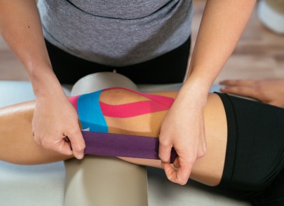 Chiropractor applying Rock Tape to patient's knee