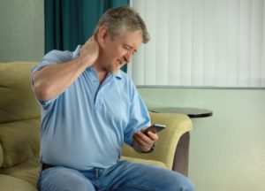 man holding phone with neck pain