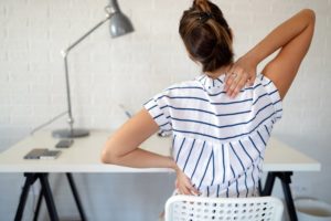 woman sitting at a desk with back pain