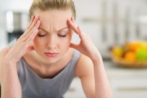 woman experiencing a tension headache and needing to visit the chiropractor